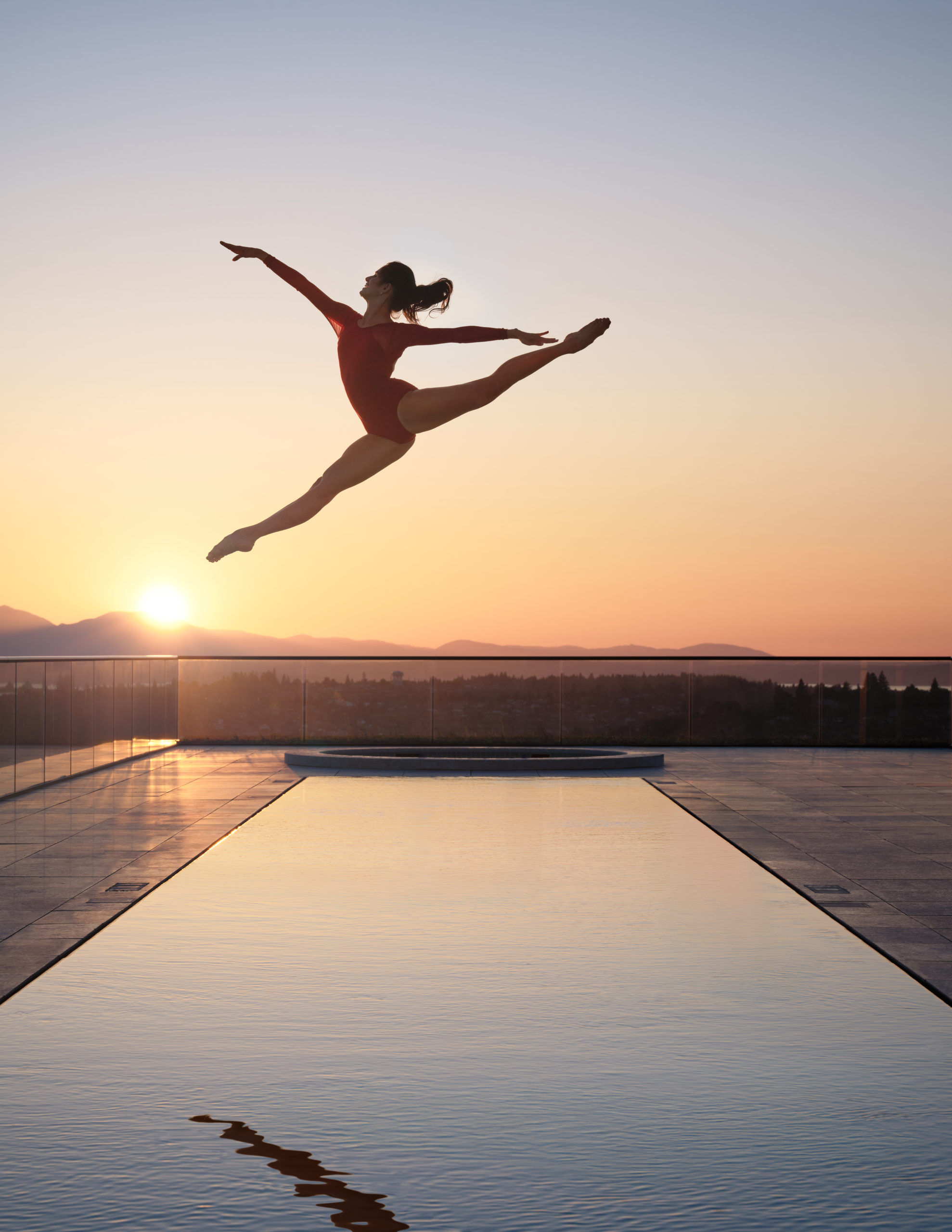 A dancer above the First Light rooftop pool against the Seattle sunset
